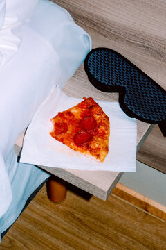 from a high angle, bitten pepperoni pizza rests beside a sleep mask