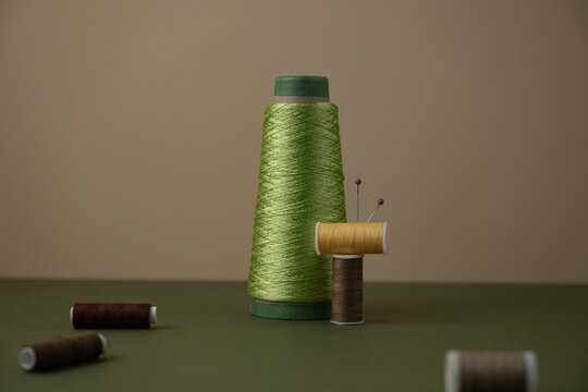Sewing Thread Spools and Pins  on a textured surface