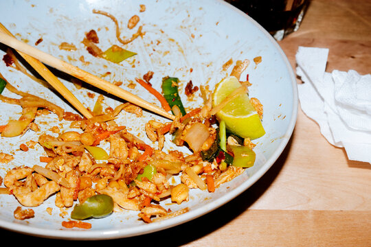 a nearly empty plate of chicken pad thai after a restaurant meal