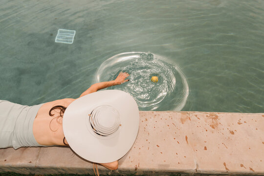 Person Relaxing by Poolside in Sun Hat
