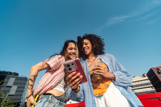 Two Friends Looking at phone Outdoors on a Sunny Day
