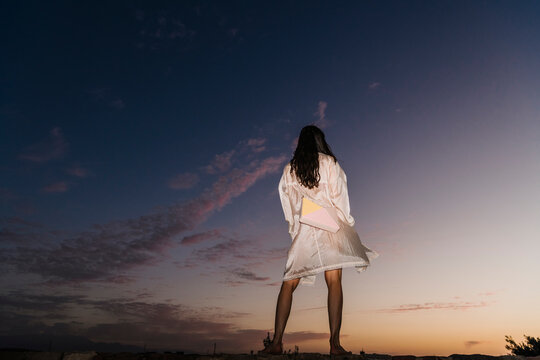 Solo Figure Standing At Sunset With Purse