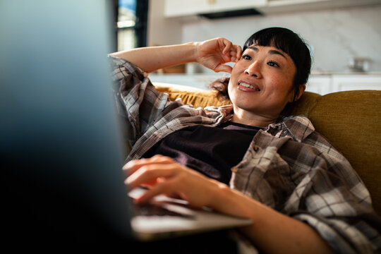 Smiling woman using laptop on couch at home