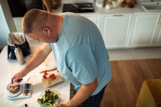 Man weighing ingredients on a kitchen food scale at home