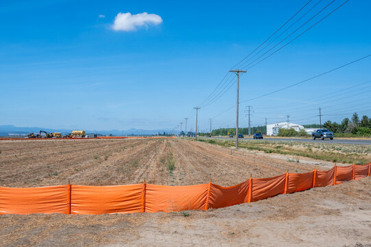 Eugene, Oregon, United States - 16 August 2026: View of the construction site for the new Amazon warehouse center near Eugene Airport, with orange silt fencing and construction equipment.