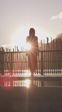 Luxury resort high end hotel rich people lifestyle woman tourist relaxing watching sunset on private balcony of overwater bungalow suite in Bora Bora, Tahiti, French Polynesia. Raw real vertical video