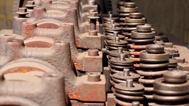Panning shot of an industrial diesel engine cylinder head showing rows of valve springs, retainers, and cast iron bearing caps.