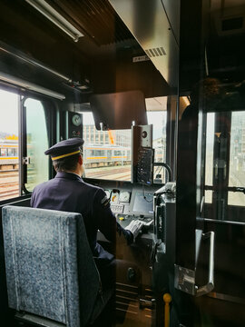 Takayama, Gifu, Japan - 01 September 2026: View of a train driver in uniform operating the controls inside the cockpit at Takayama Station, with tracks visible through the window.