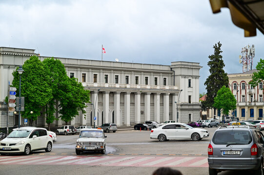 A classic theater building with a columned facade in the city center of Telavi, with street traffic and parked cars in the main square, Kakheti, Georgia 15.08.2025
