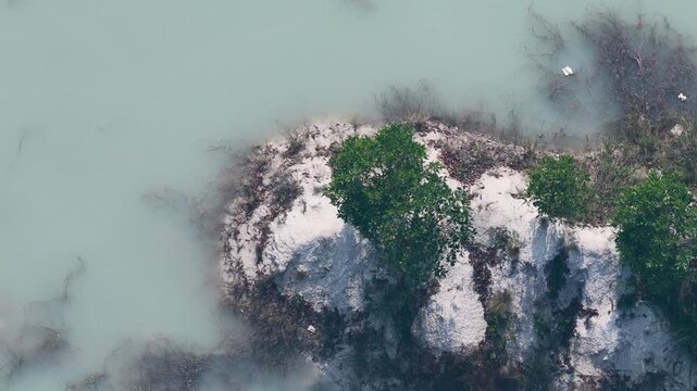 Small island with green trees surrounded by clear blue water in South Kalimantan Indonesia