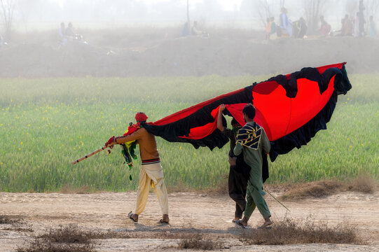 Okara, Punjab, Pakistan - 13 March 2024: View of devotees carrying a large red and black flag during the annual Urs festival at the shrine of Hazrat Daud Bandagi Kirmani.