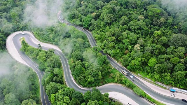 Aerial view of the winding Panatapan Berastagi road surrounded by lush tropical forest and dense vegetation in Berastagi, North Sumatra, Indonesia.