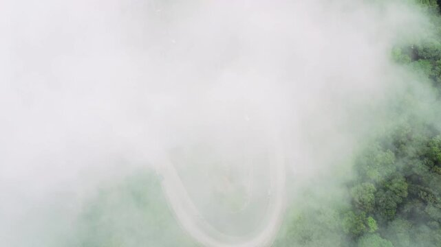 Aerial view of a winding road through the misty forest at Panatapan Berastagi in Berastagi, North Sumatra, Indonesia.