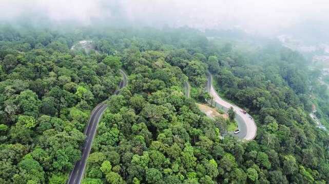 Aerial view of the winding Panatapan Berastagi road cutting through the lush green forest in Berastagi, North Sumatra, Indonesia.