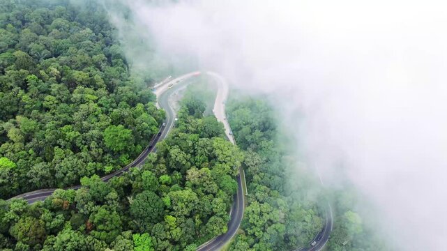 Aerial view of Panatapan Berastagi winding road through dense forest and mist in Berastagi, North Sumatra, Indonesia.