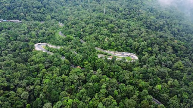 Aerial view of the winding road at Panatapan Berastagi surrounded by dense tropical forest in Berastagi, North Sumatra, Indonesia.