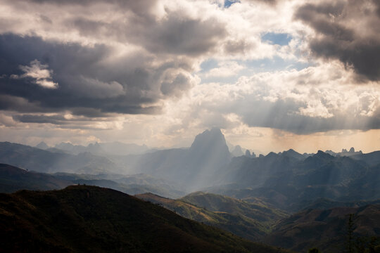 Laos - 31 December 2024: View of dramatic mountain ranges with sunbeams breaking through heavy clouds over the rugged landscape.