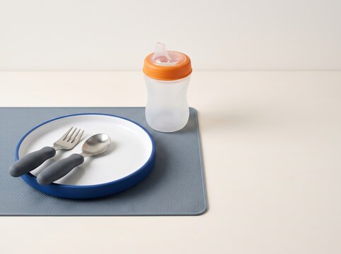 Toddler utensils and sippy cup arranged on silicone placemat
