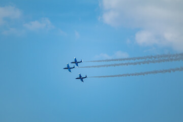 Fototapeta premium Three jet aircrafts together in formation with smoke trails contrasting against a scenic blue sky on airshow