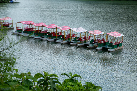 Pokhara, Nepal - 31 July 2026: View of a row of colorful pedal boats with red canopies floating on the calm water of Phewa Lake in Pokhara, Gandaki Province, Nepal.