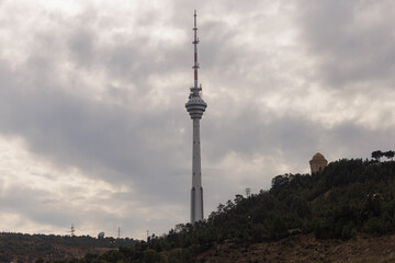 Obraz premium Majestic tower rises above green landscape under a moody sky, showcasing urban engineering wonders