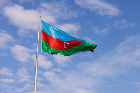 Proud Azerbaijan flag waving against a vibrant blue sky on a sunny afternoon