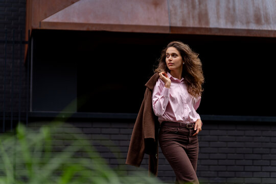 Young woman holding jacket over shoulder looking away outdoors