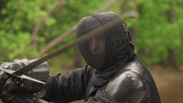 Close up of person in black fencing gear engaging in swordplay with another fencer demonstrating various techniques and movements. scene features detailed close ups of subjects protective