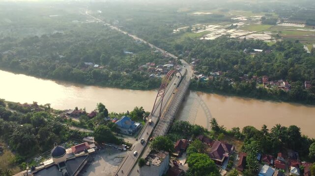 Aerial view of Wampu River Bridge Binjai - Langsa Toll Road spanning the river with surrounding lush greenery and rural landscape Stabat, North Sumatra, Indonesia.