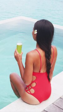 Beer. Woman drinking beer having fun in hotel pool by relaxing and drinking beer. Luxury resort travel vacation concept. Raw unedited vertical video of real unretouched woman model without any makeup