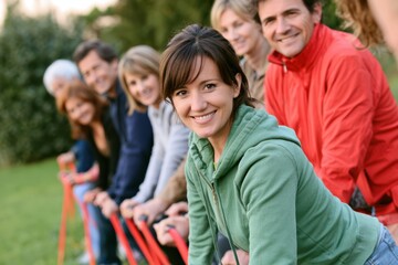 Fototapeta premium Group of diverse adults smiling and posing together outdoors, with green grass and trees in the background, showcasing a sense of community and togetherness
