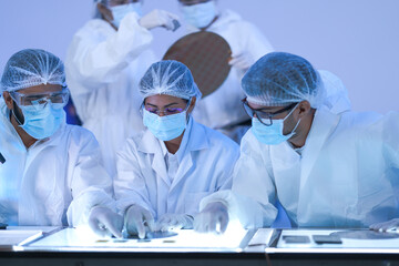 A semiconductor inspection team raise a wafer to the light for quality control in a high-technology...