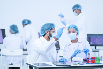 A pair of research scientists handle petri dishes and reagent tubes in a bright modern laboratory...