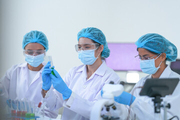 Lab technicians review results on a tablet by the microscope in a clean modern science lab while...