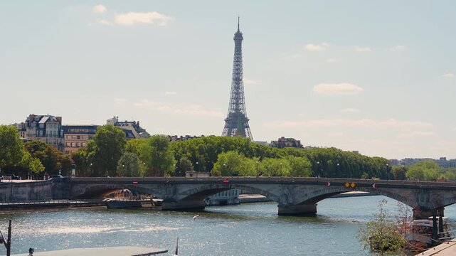 Scenic wide view of the iconic Eiffel Tower rising behind Pont des Invalides bridge and the Seine River in Paris, France. High quality 4K video on a sunny day