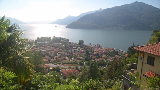 Lake Maggiore panorama with Maccagno town, mountains and sun reflection on waterand distant Cannero Islands, scenic landscape in Lombardy, Italy