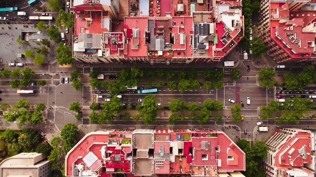 Aerial view of busy city streets with red rooftops and green trees in Barcelona, Catalonia, Spain.