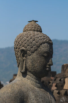 Close-Up of Ancient Stone Buddha Statue Head Against Distant Hills at Borobudur Temple in Central Java near Yogyakarta Indonesia
