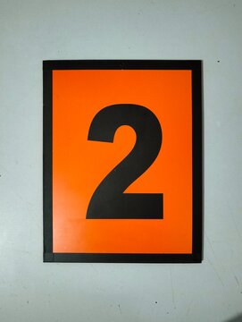 Rectangular orange sign with stylized black symbol resembling number two