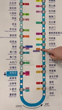Traveler pointing at a station on the Beijing subway map while planning a route using public transportation in Beijing, China.
