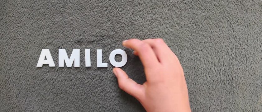 persona escribiendo la palabra amiloidosis en un fondo texturizado y oscuro con letras blancas y pre hechas (version rapida)