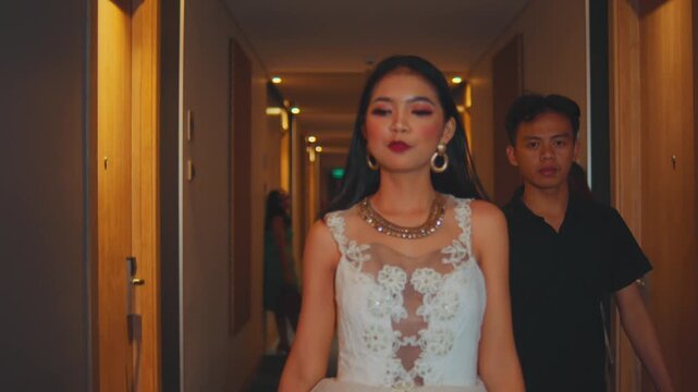 Woman in White Dress Accepts Red Condom Packet in Hallway