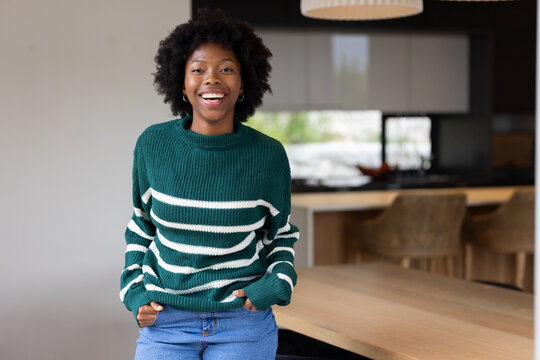 African American woman standing in kitchen wearing green striped sweater, hands tucked