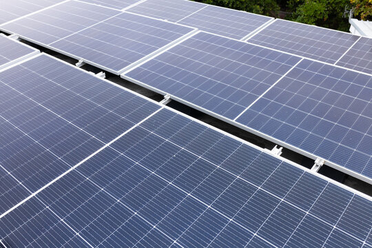 Roof-mounted solar panels are reflecting bright daylight with visible cell grids and metal rails