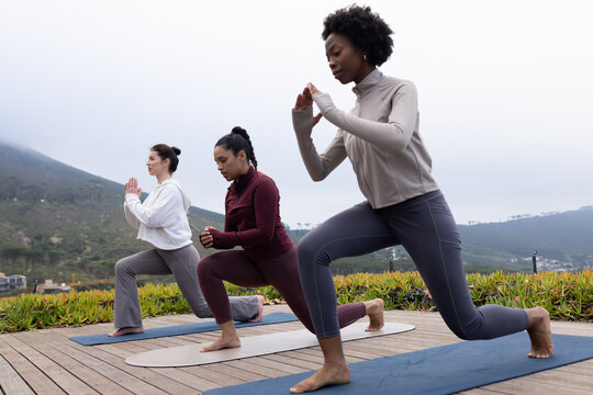African American women practicing lunges in leggings on deck with mats and succulents, copy space