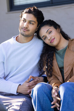 African American couple sitting on bench outside by window blinds, woman resting head