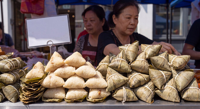 Large stacks of freshly wrapped pyramid shaped rice dumplings wrapped in bamboo leaves sold at an authentic outdoor food stall