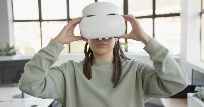 Adult nonbinary African raising white VR headset adjusting fit gesturing to control AR menu at desk