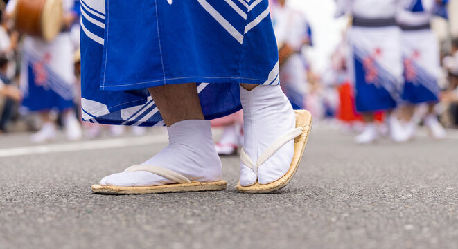 Low angle view of feet of dancers wearing traditional white split toe tabi socks and woven straw zori sandals marching synchronously during festival parade