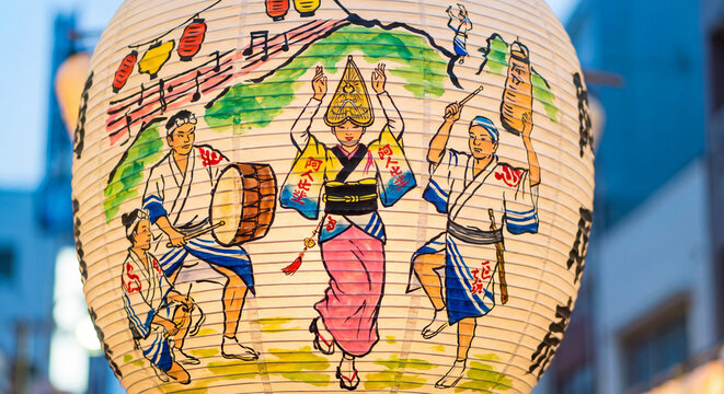 Close up of traditional round Japanese paper lantern chochin decorated with colorful hand painted illustrations of energetic folk dancers during Awa Odori festival